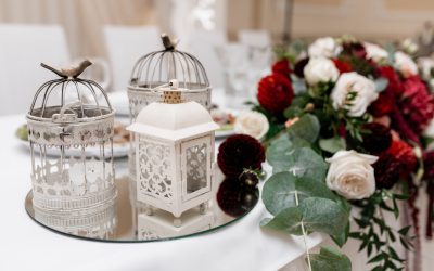 Floral composition with eucalyptus, white and bordeaux roses on the table and metal cages on a mirror